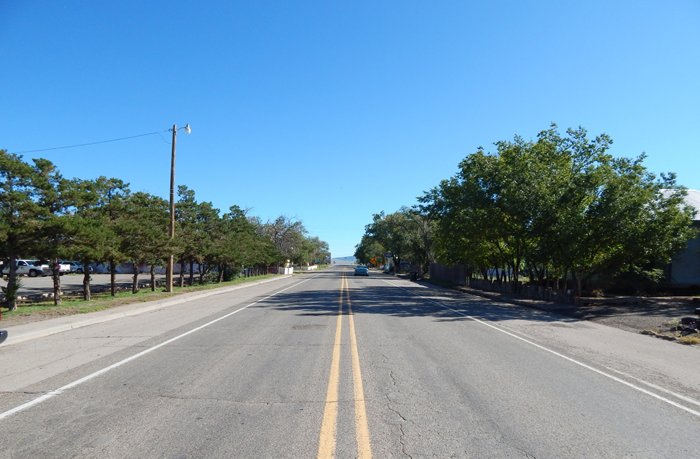 Photo taken from middle of highway with trees on either side